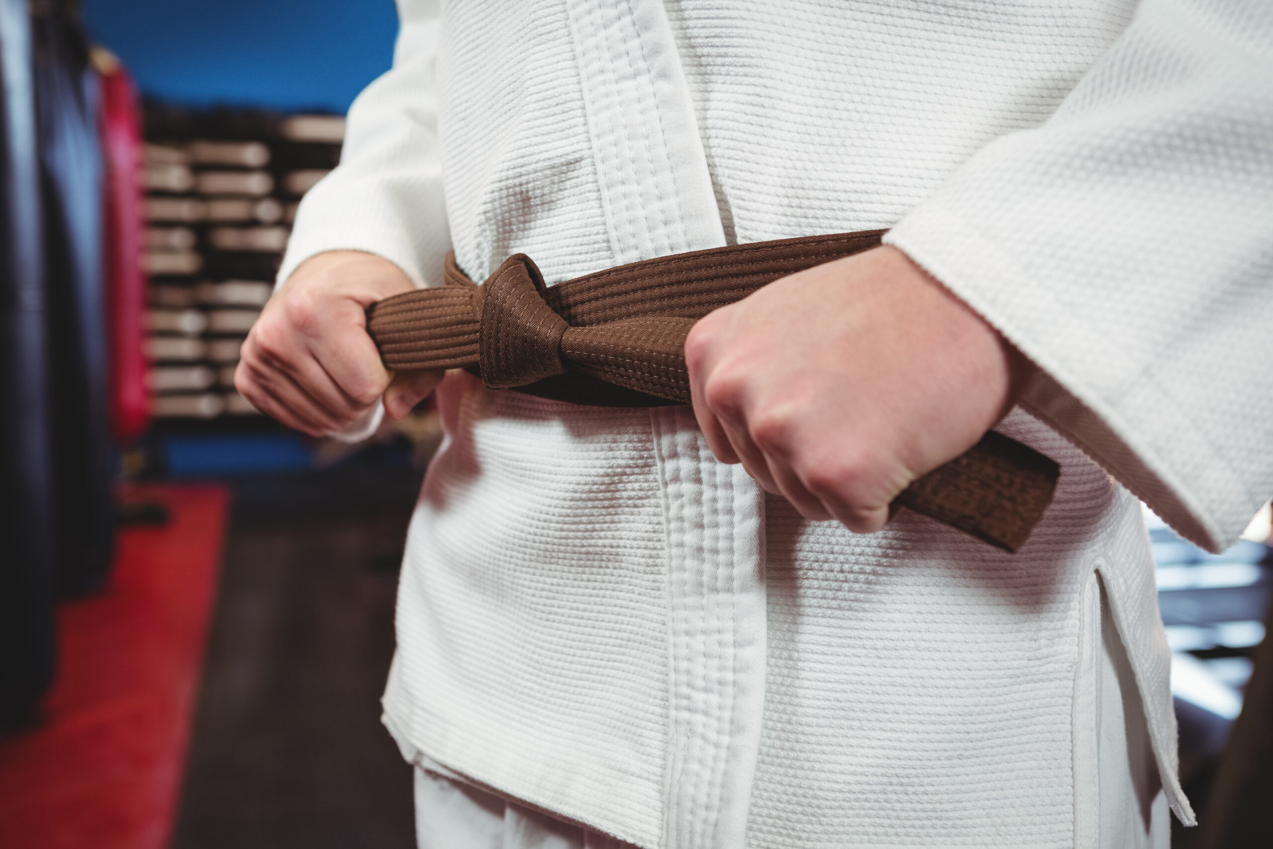 Mid section of karate player tying his belt in fitness studio